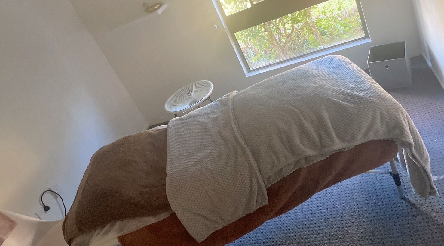 Cozy massage room at ＷＡＲＭ 1.3 in Kirwan, Queensland, AU with a plush bed and sunlight streaming through the window.