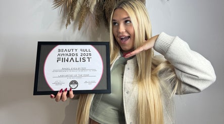 Excited recipient holds beauty award certificate at Angel Collective, Bournemouth, England, GB.