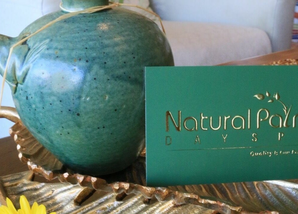 Green vase and spa card at Natural Palm Day Spa, Cairns City, Queensland, AU; evokes relaxation and luxury.