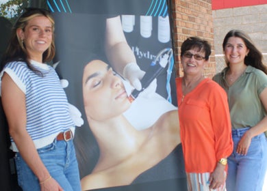 Staff outside The Skin Bar and Body Boutique LLC, Johnson City, Tennessee, US, beside a skincare poster.