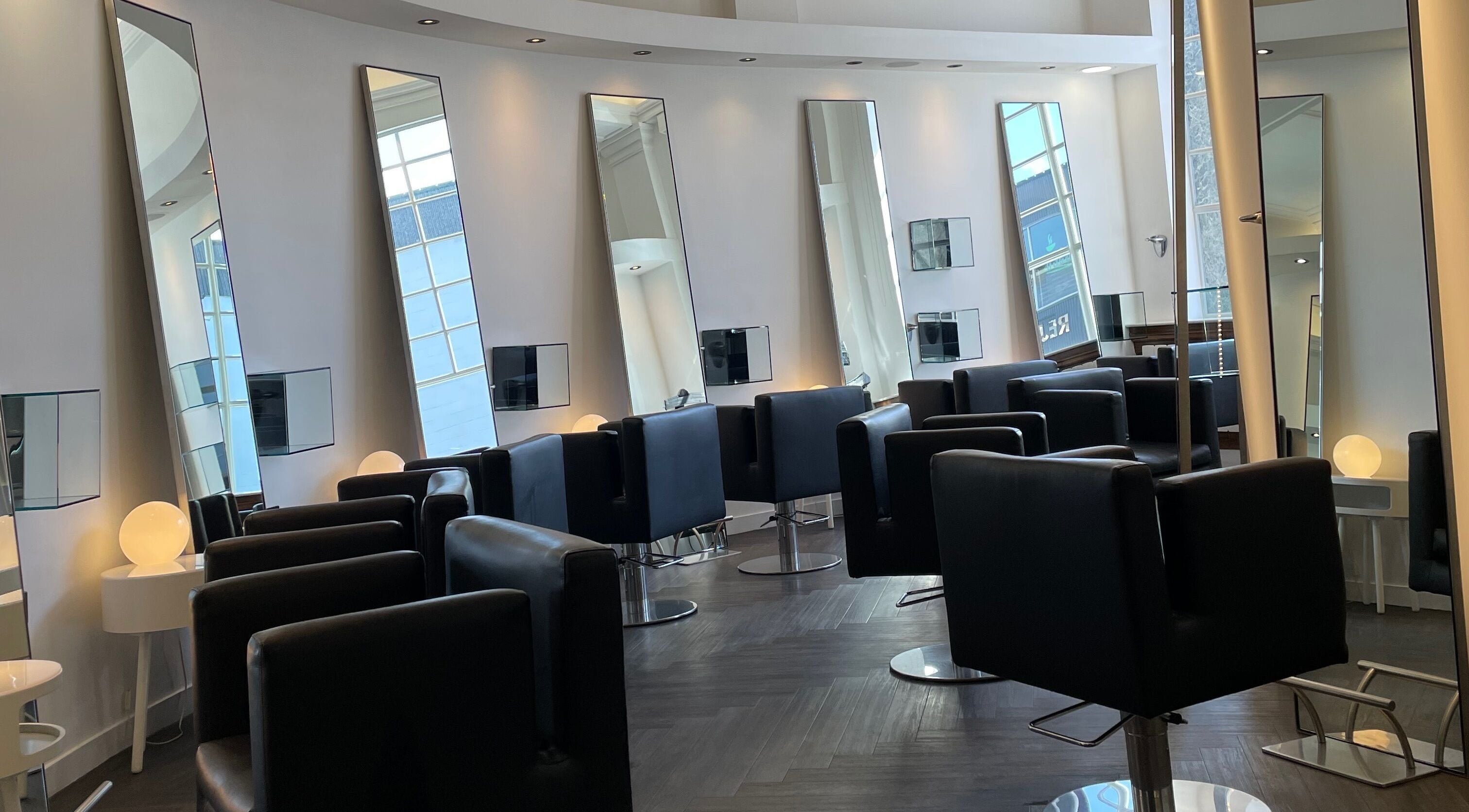 Modern salon styling chairs at The Bank Hair & Beauty, Kirkcaldy, Scotland, GB with sleek mirrors.