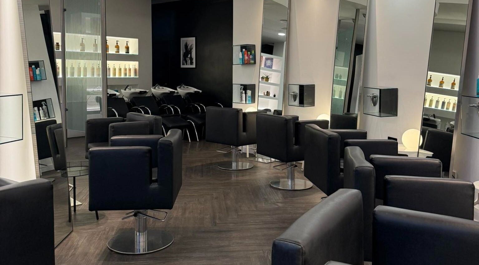 Modern salon interior at The Bank Hair & Beauty, Kirkcaldy, Scotland, GB showcases sleek chairs and styling stations.