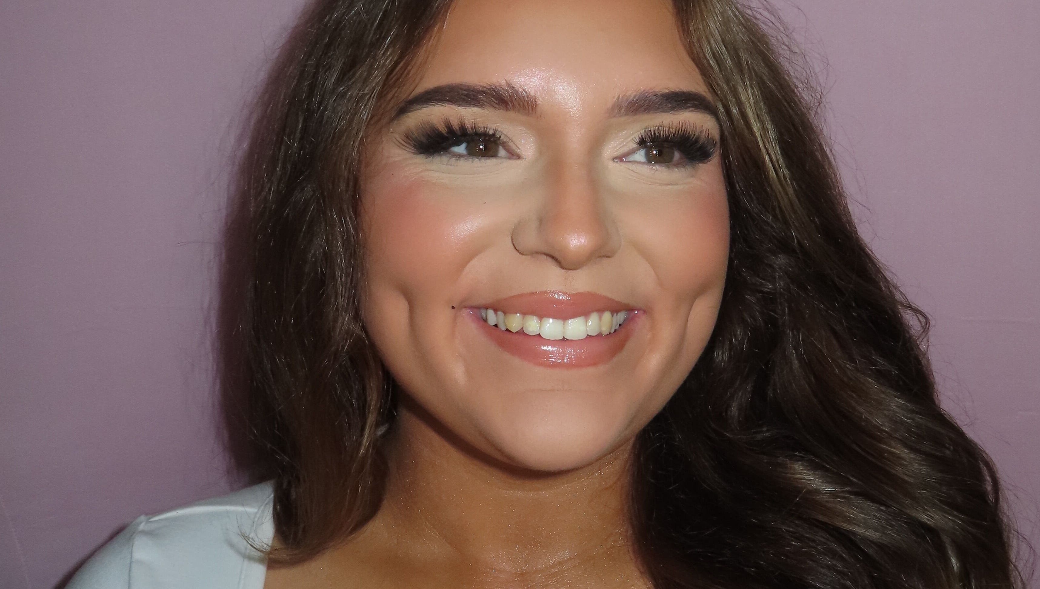 Close-up of a smiling woman showcasing flawless makeup at Dazzle Den, Douglas, Douglas, IM.