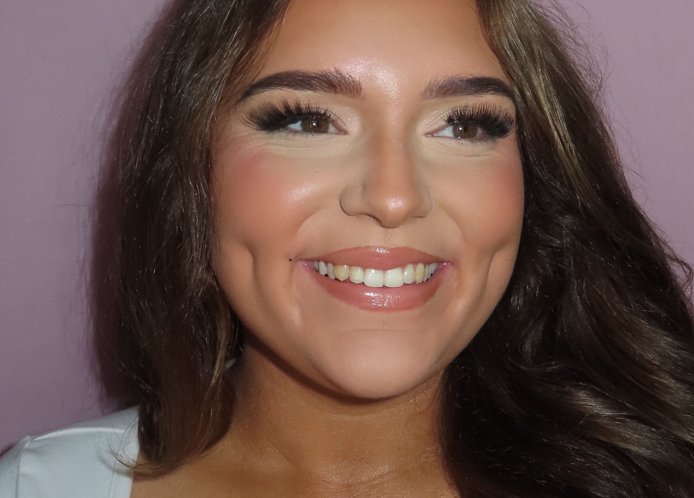 Close-up of a smiling woman showcasing flawless makeup at Dazzle Den, Douglas, Douglas, IM.
