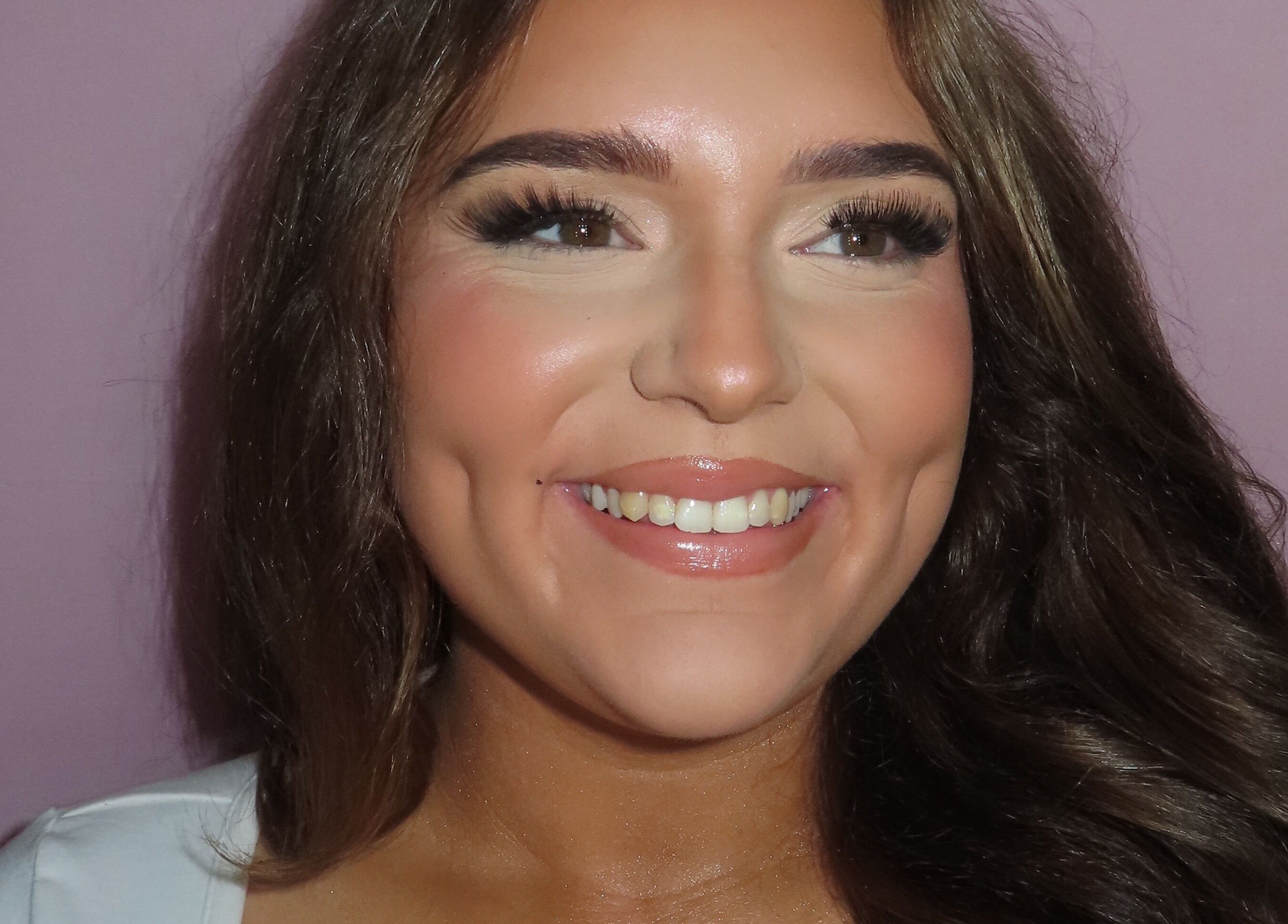 Close-up of a smiling woman showcasing flawless makeup at Dazzle Den, Douglas, Douglas, IM.