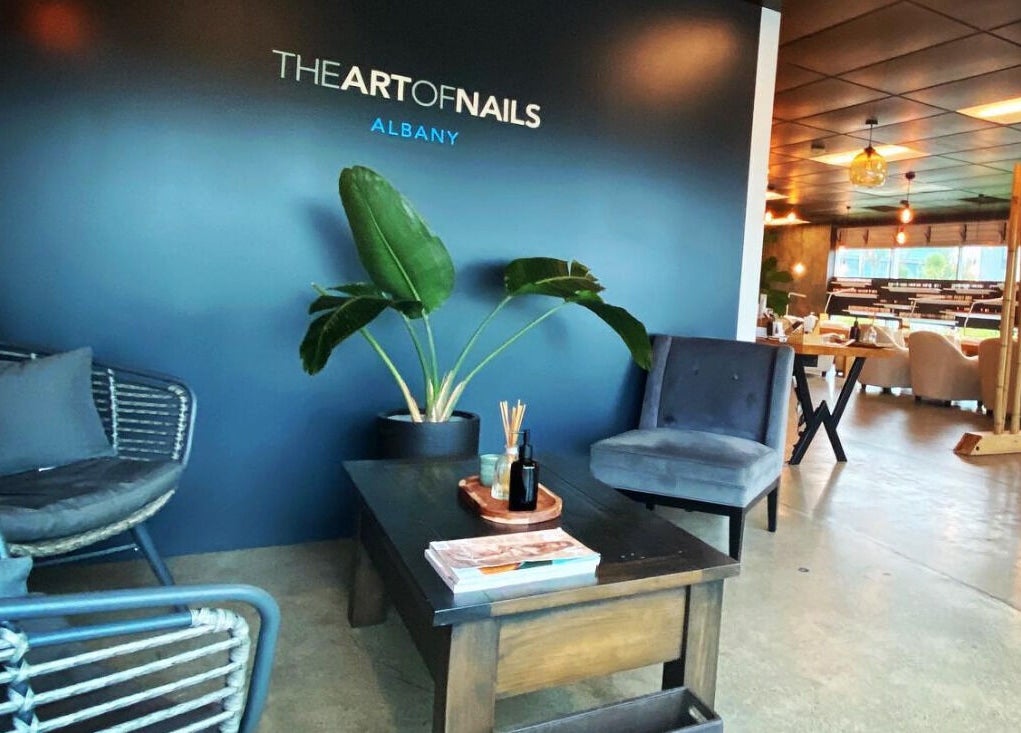 Lounge area at The Art of Nails Commercial Bay, Auckland, NZ, featuring cozy seating and stylish decor.