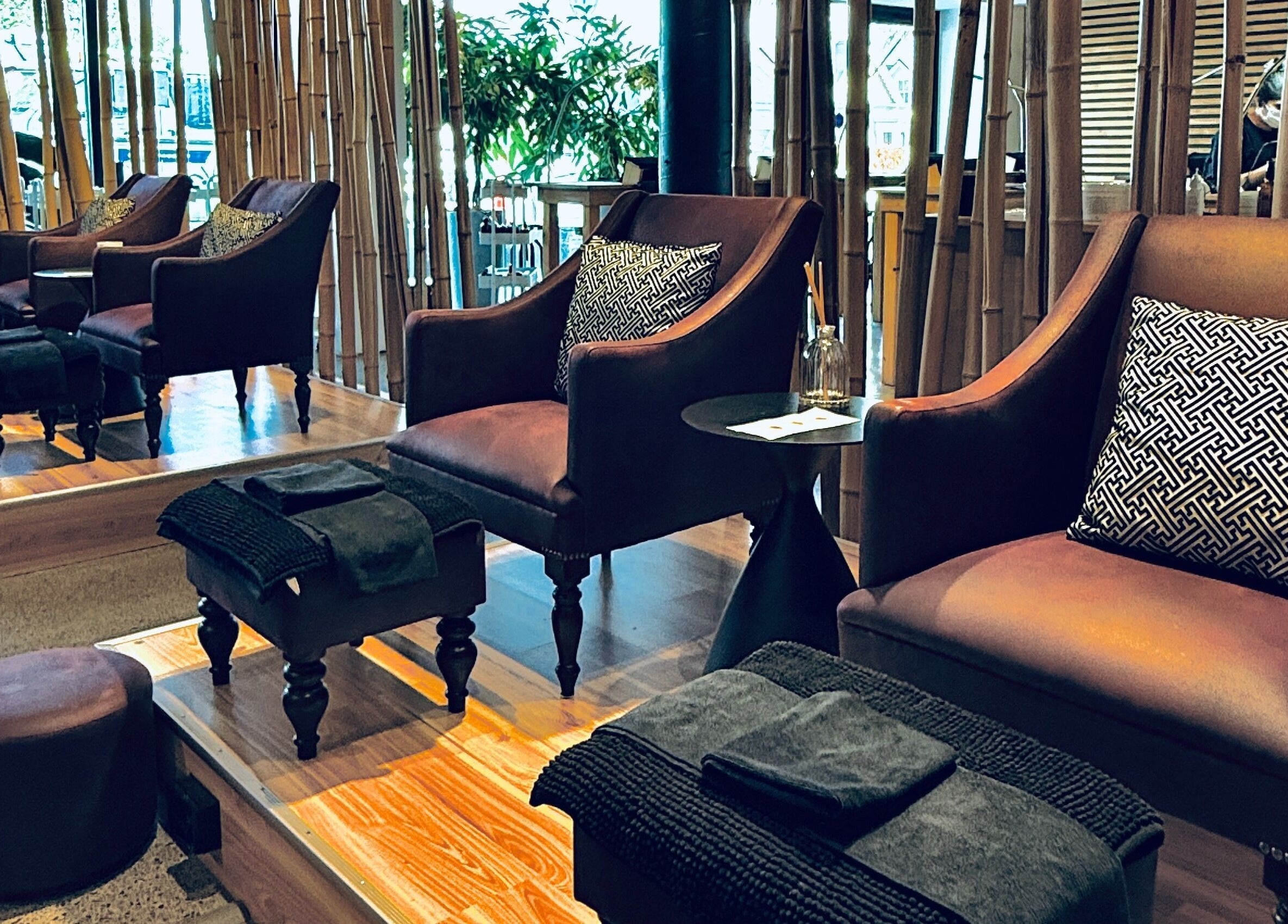 Luxurious seating at The Art of Nails Ponsonby, Auckland, NZ, showcasing plush chairs and bamboo decor.