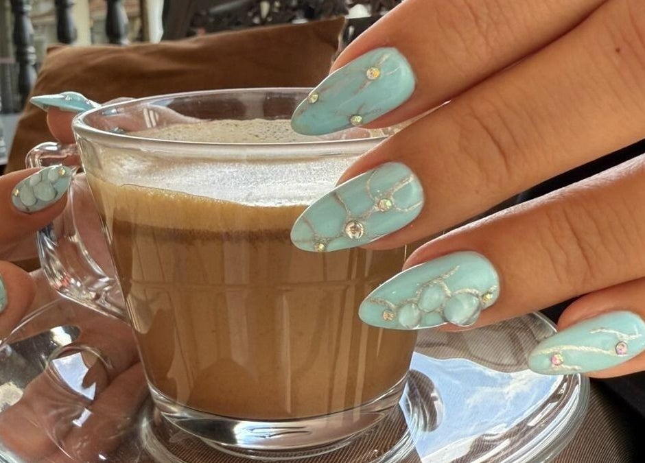 Elegantes uñas azules decoradas sosteniendo una taza de café en Moments The Nails Place Escazu, San Rafael, San José, CR.