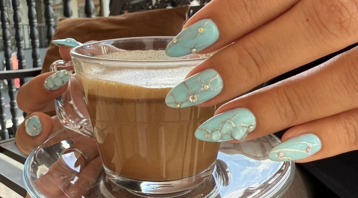 Elegantes uñas azules decoradas sosteniendo una taza de café en Moments The Nails Place Escazu, San Rafael, San José, CR.