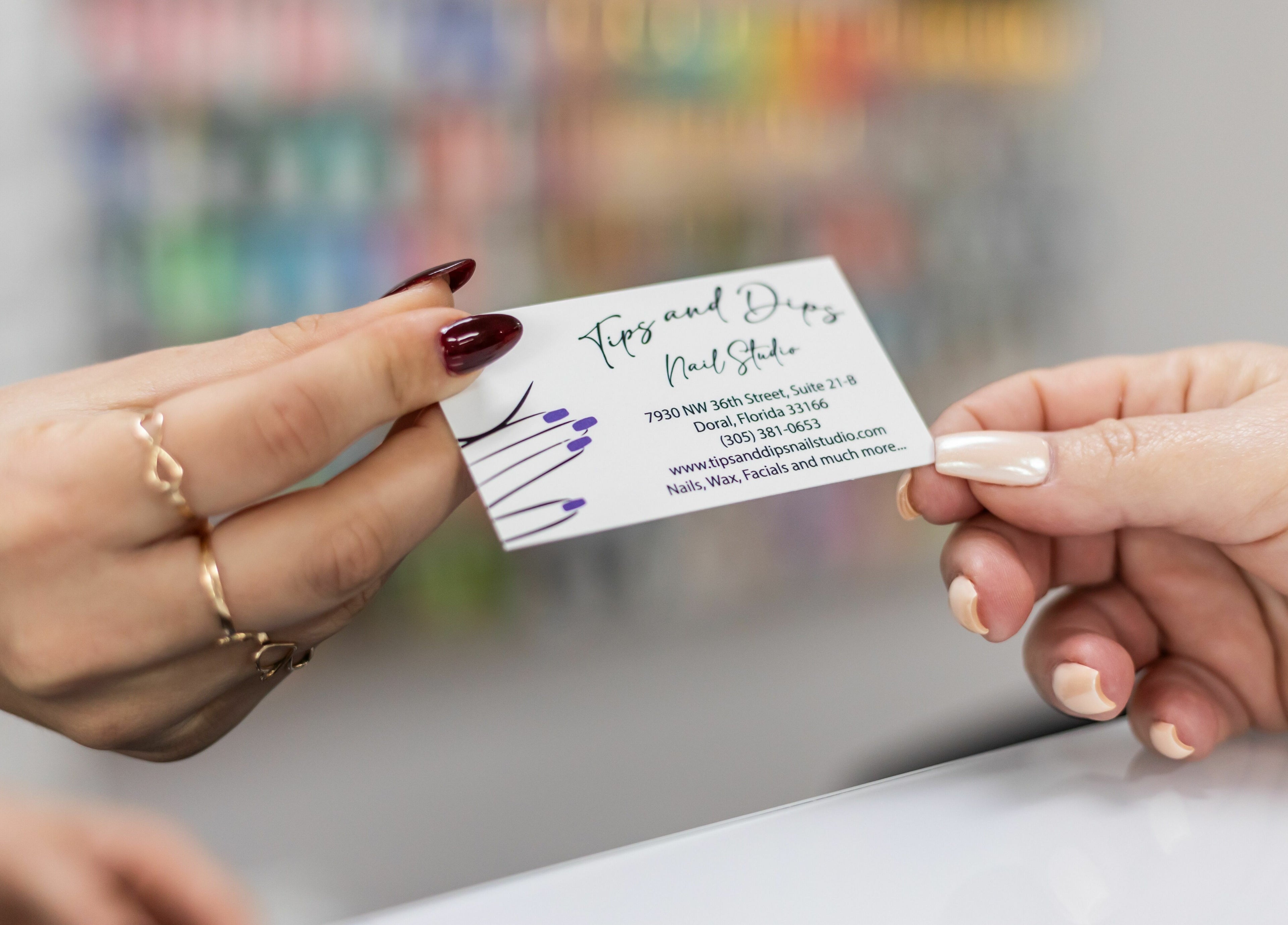 Client exchanging business card at Tips & Dips Nail Studio, Doral, Florida, US; showcasing nail art expertise.