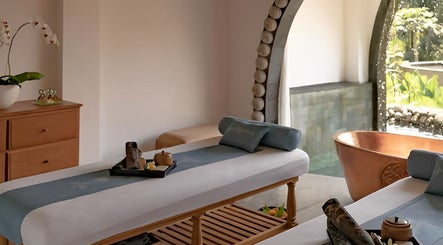 Luxurious spa room at Dirasha Wellness in Bali, Bali, ID, featuring massage beds and a copper bathtub.