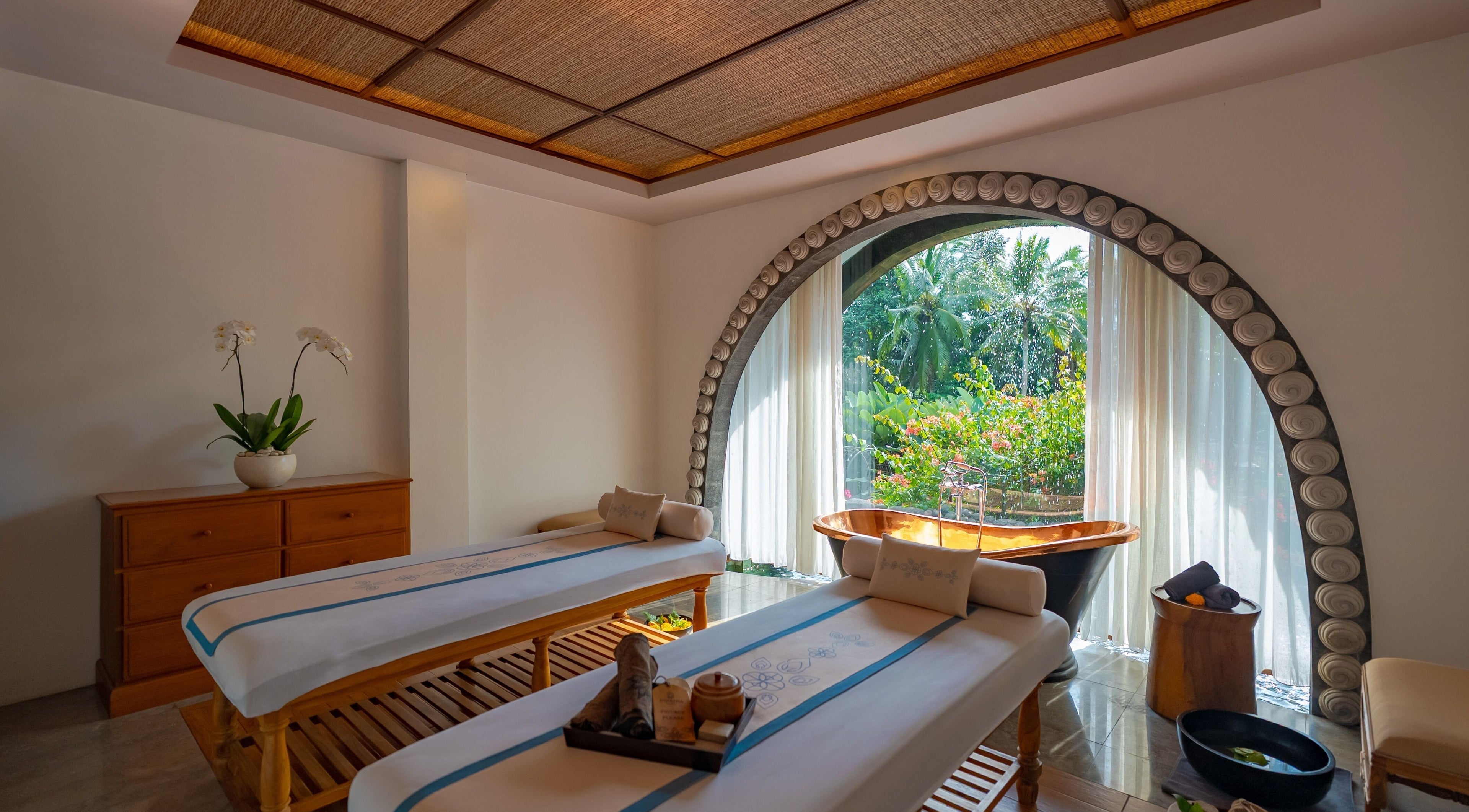Relaxing massage room at Dirasha Wellness in Bali, Bali, ID with a garden view and soaking tub.