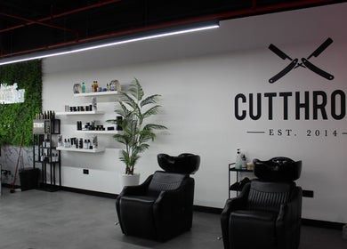 Modern interior of Cutthroat salon in Dubai, Dubai, AE with stylish chairs and product shelves.