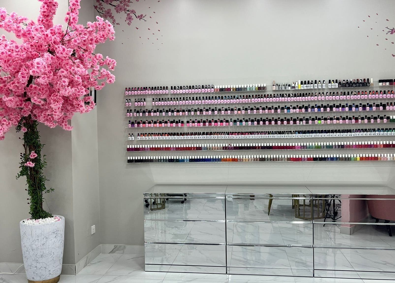 The Pinky Beauty Lounge in Abu Dhabi, AE features a vibrant nail polish wall with cherry blossom decor.