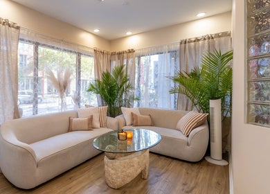 Salon élégant à Skines Head Spa, Montréal, Québec, CA, avec canapés beige et plantes luxuriantes.