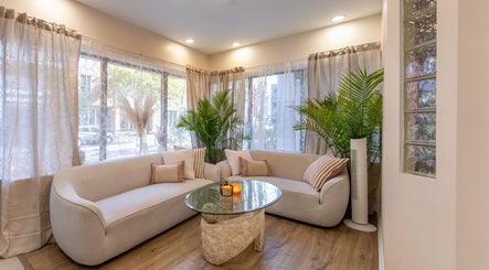 Salon élégant à Skines Head Spa, Montréal, Québec, CA, avec canapés beige et plantes luxuriantes.