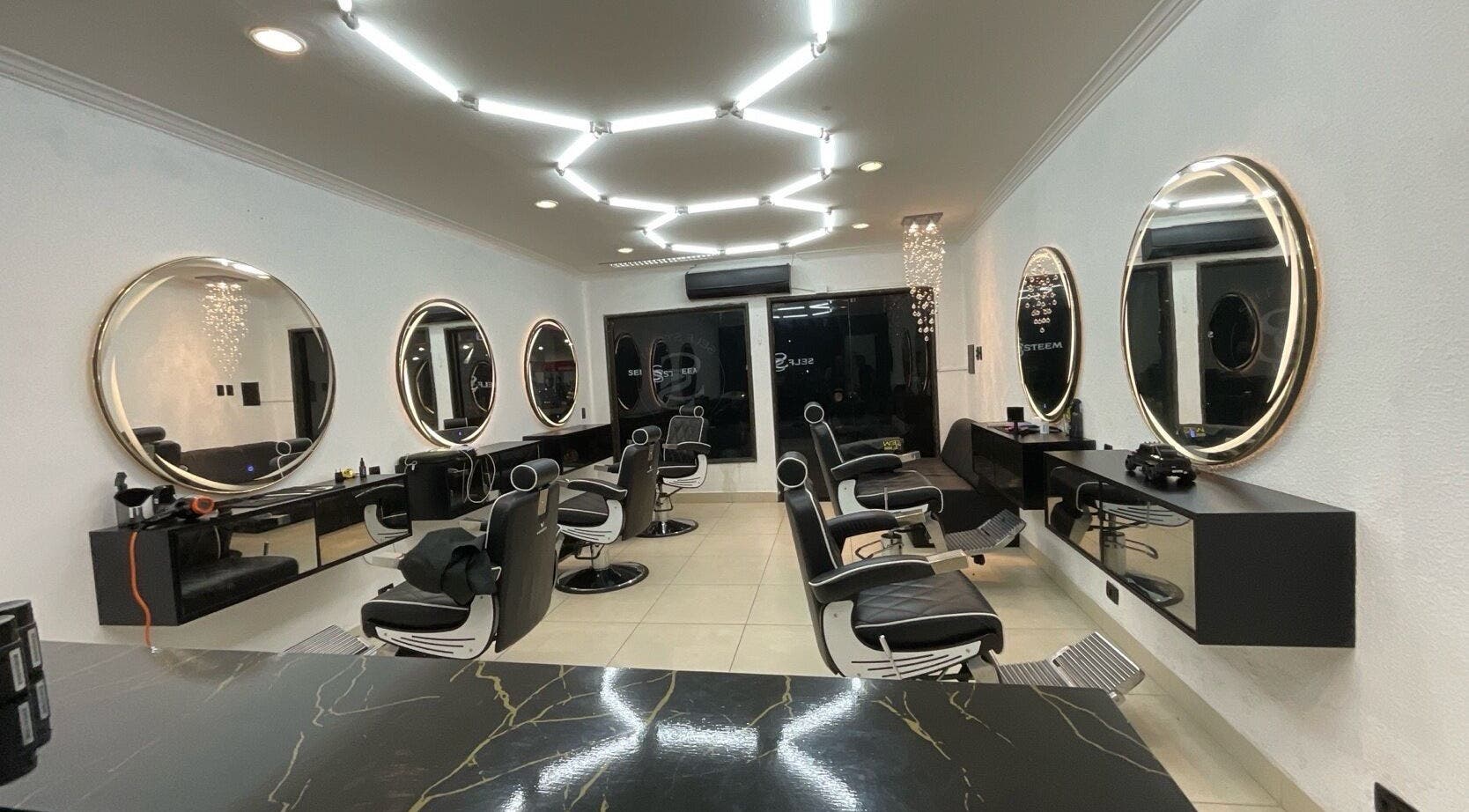 Interior moderno do salão Self Steem em Rondônia, Rondônia, BR, com espelhos circulares e cadeiras alinhadas.