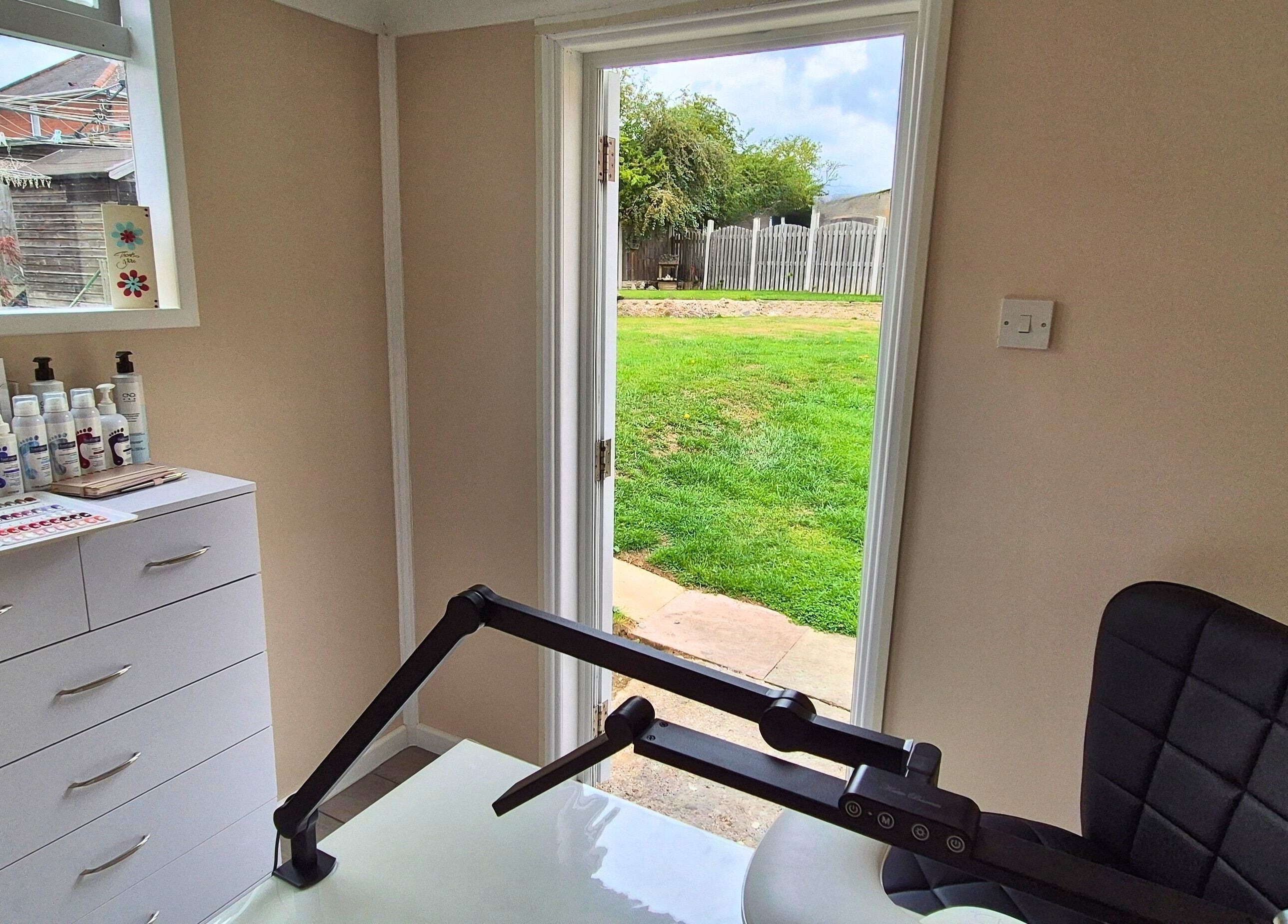 Bright workspace at Fingers and Toes, Mexborough, England, GB with garden view and beauty products.