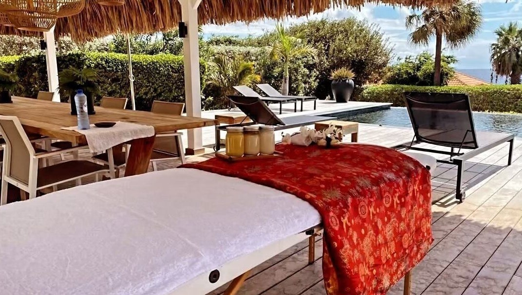 Buitenterras van Pura Vida by Johanny, Willemstad, Curaçao, CW met massagebed en zwembadzicht.