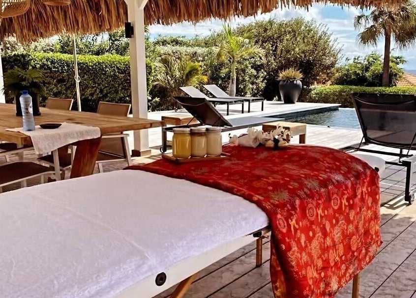 Buitenterras van Pura Vida by Johanny, Willemstad, Curaçao, CW met massagebed en zwembadzicht.