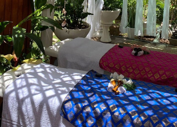 Rustgevende massagebedden bij Pura Vida by Johanny, Willemstad, Curaçao, CW, omgeven door groene planten.