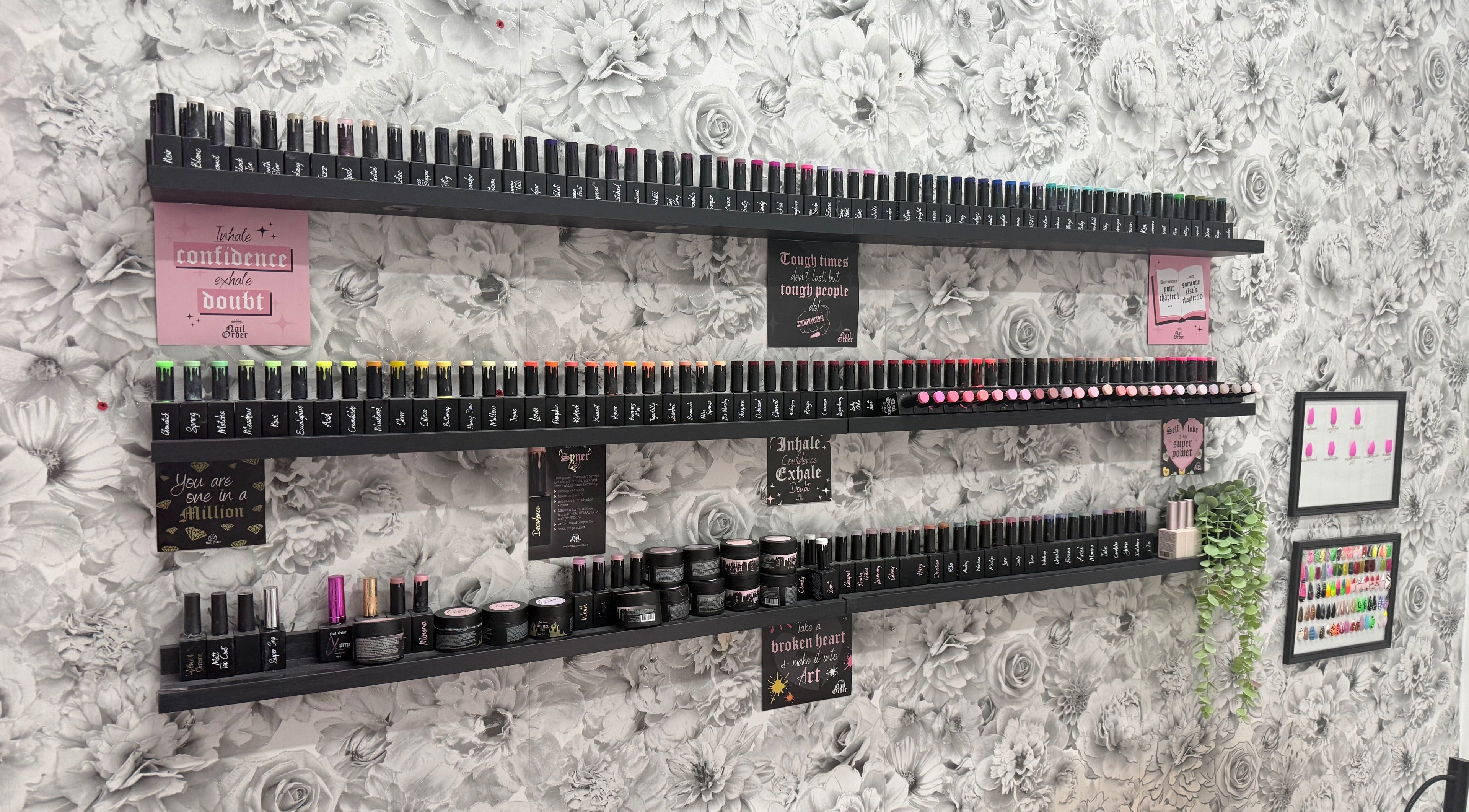 Elegant nail polish collection at Nails by Emma, Norton, England, GB, set against floral wallpaper.