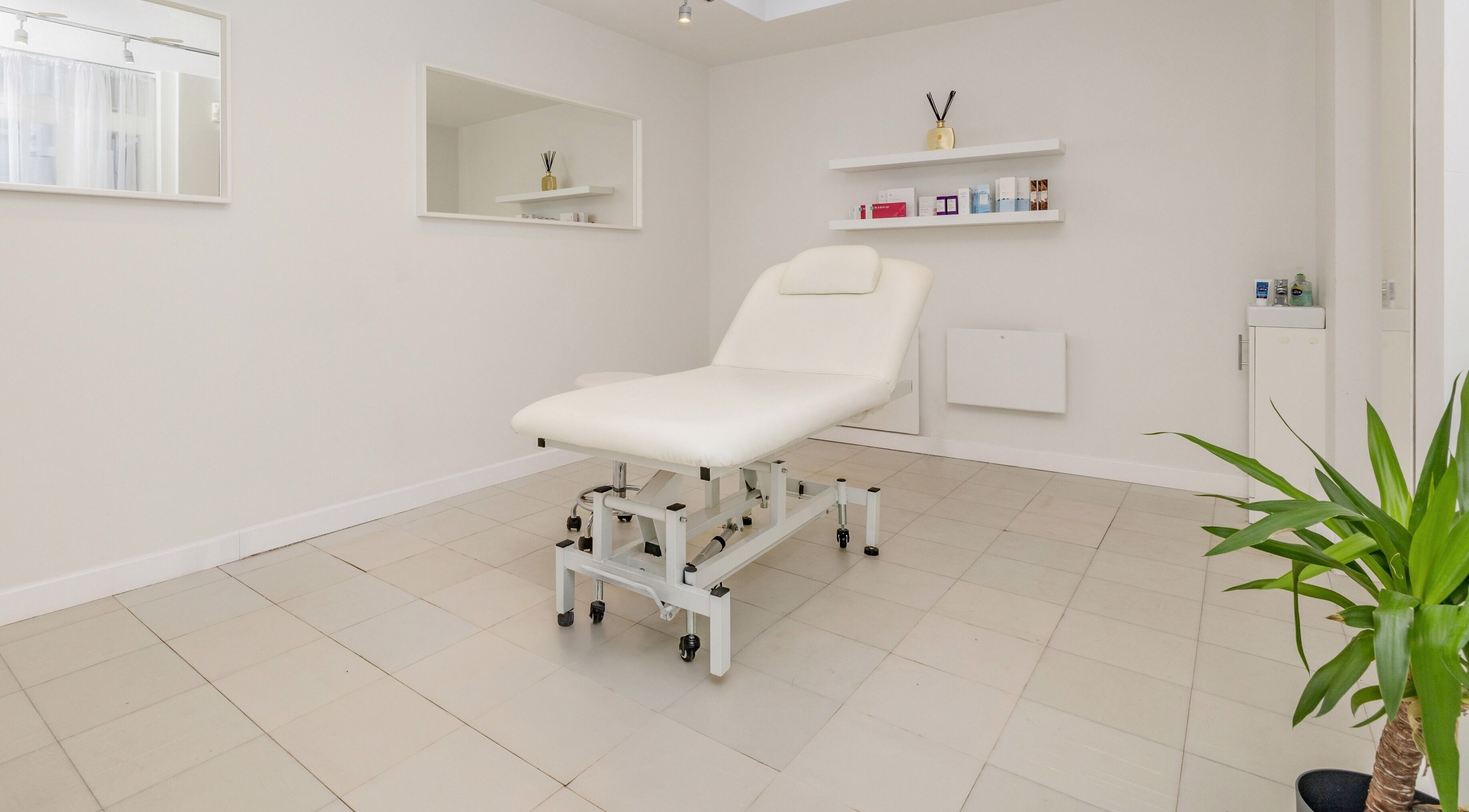 Calm treatment room at Nüseoul, London, England, GB, featuring a white therapy bed and serene decor.