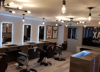 Interior of Chax Barbers on Waterloo Rd, Stoke-on-Trent, England, with modern chairs and illuminated mirrors.