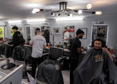 Busy interior of Chax Barbers on Waterloo Rd, Stoke-on-Trent, England, GB with clients and barbers in action.