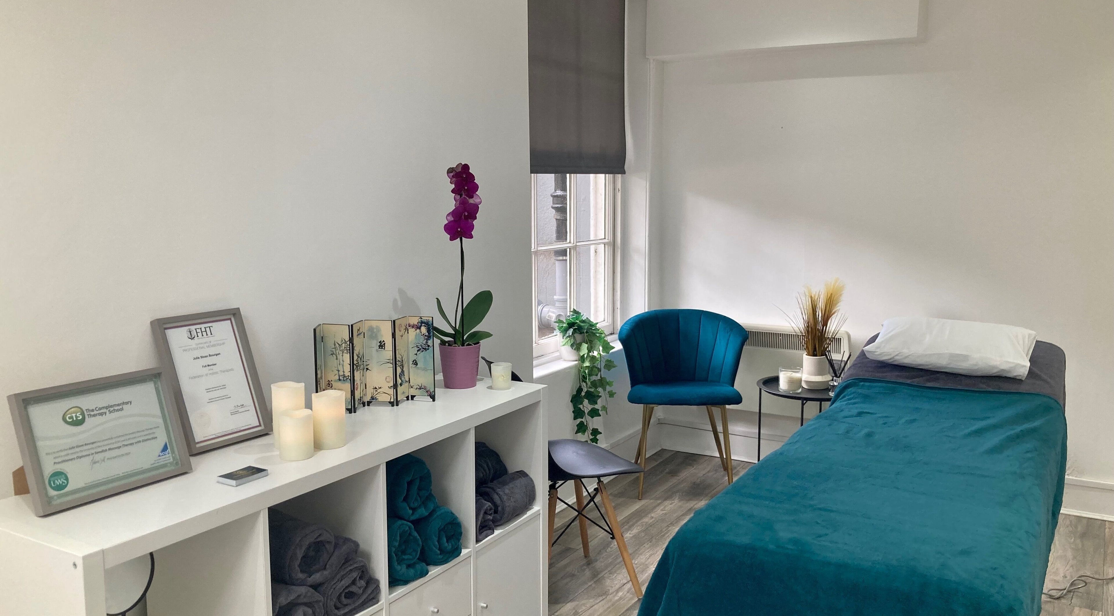 Tranquil massage room at Nirvana Massage Therapy in Aberdeen, Scotland, GB with teal accents and candles.