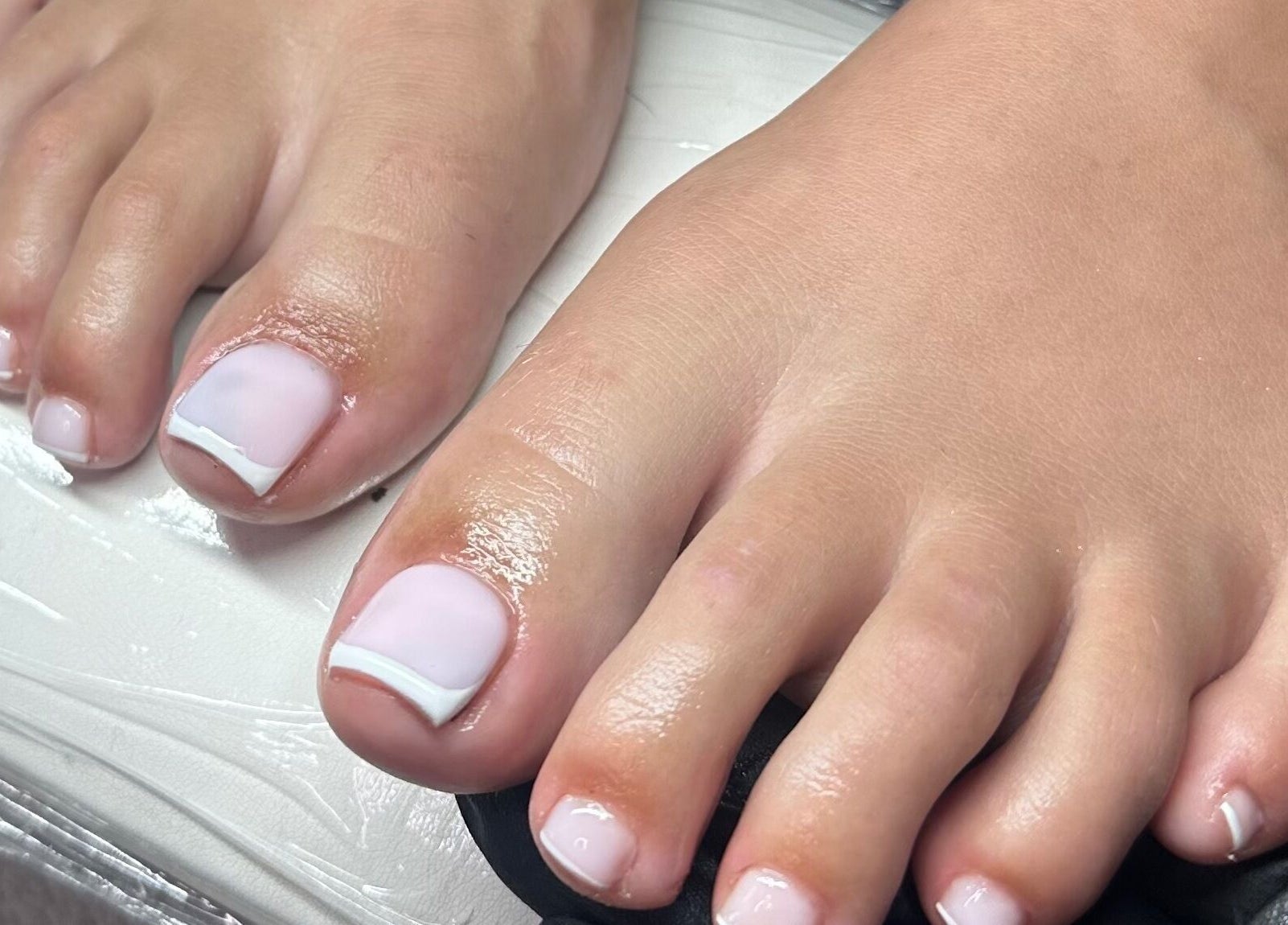 Elegant French pedicure at Glow by Mads in Abbots Langley, England, GB. Perfectly polished toes.