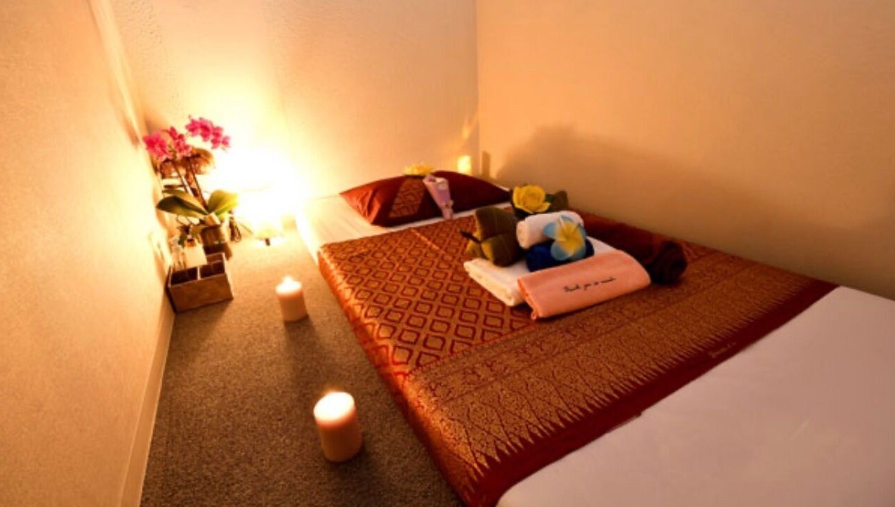 Cozy massage room at BaanMai Thai Massage and Spa, Tokyo, Minato-Ku, JP with candlelit ambiance and floral decor.