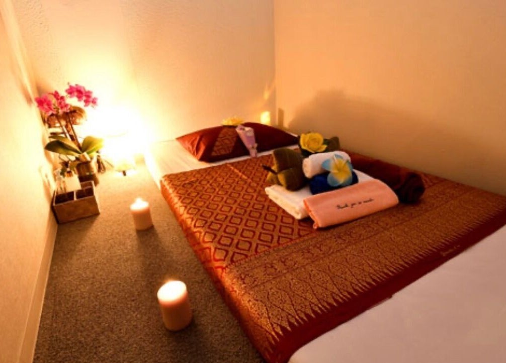 Cozy massage room at BaanMai Thai Massage and Spa, Tokyo, Minato-Ku, JP with candlelit ambiance and floral decor.