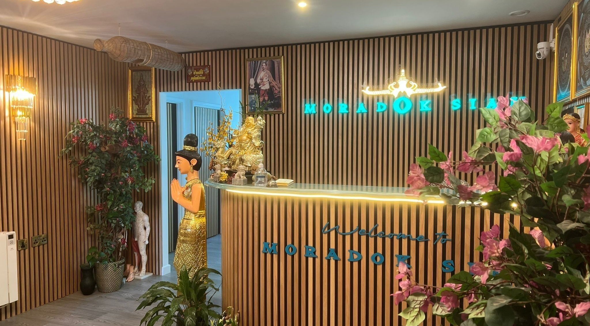 Reception area with Thai décor at Moradok Siam in Romsey, England, GB, featuring elegant sculptures and plants.