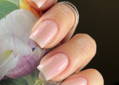 Manicura rosa suave en Mimosa Nails, Santiago, Región Metropolitana, CL, sobre fondo floral elegante.