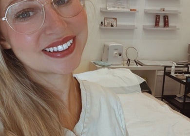 Professional at KLH Nurse Led Aesthetics clinic in Morley, England, GB with treatment bed and beauty products.