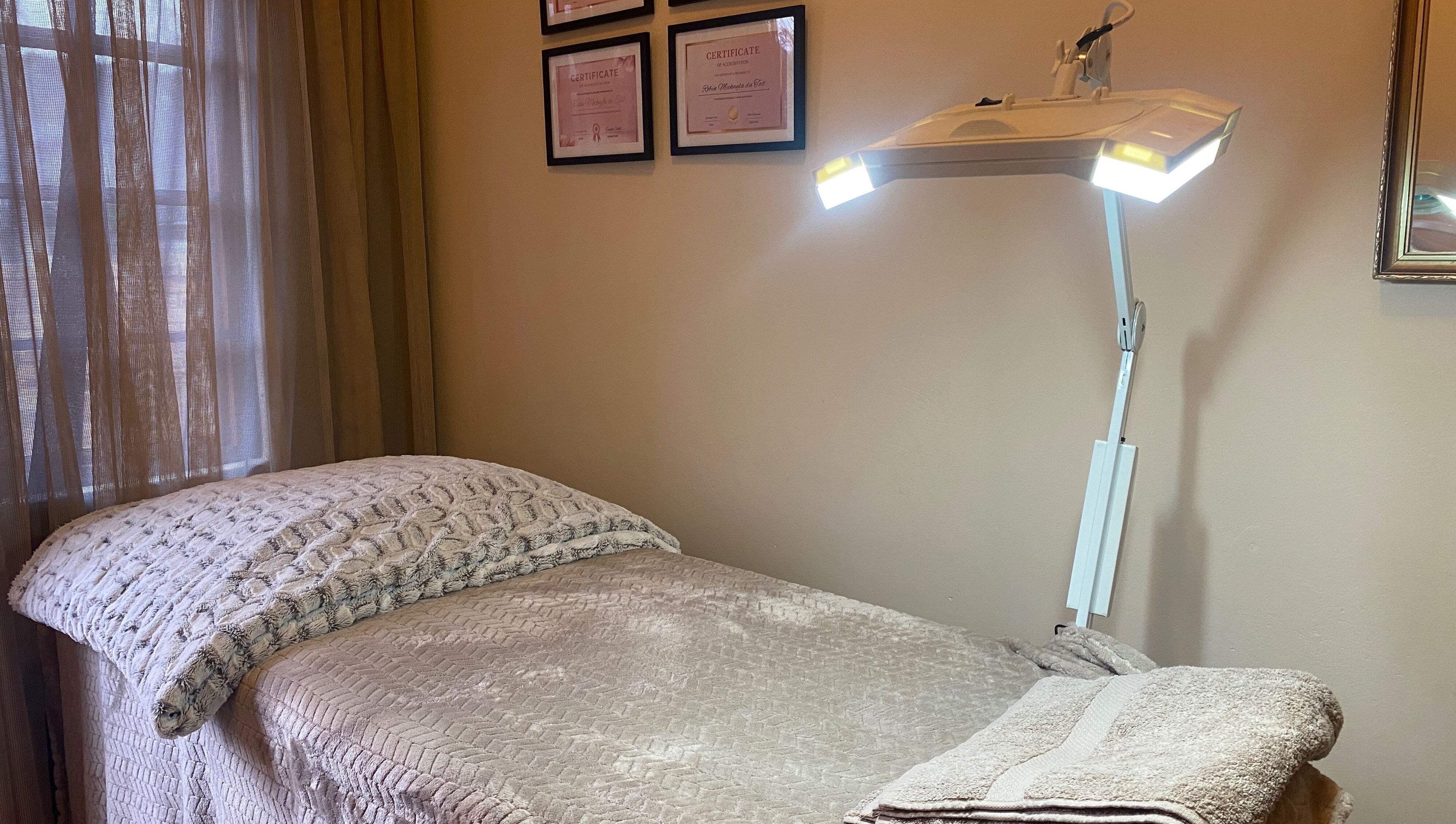 Calm treatment room at Feather Aesthetics, Bloemfontein, Free State, ZA featuring a cozy bed and soft lighting.