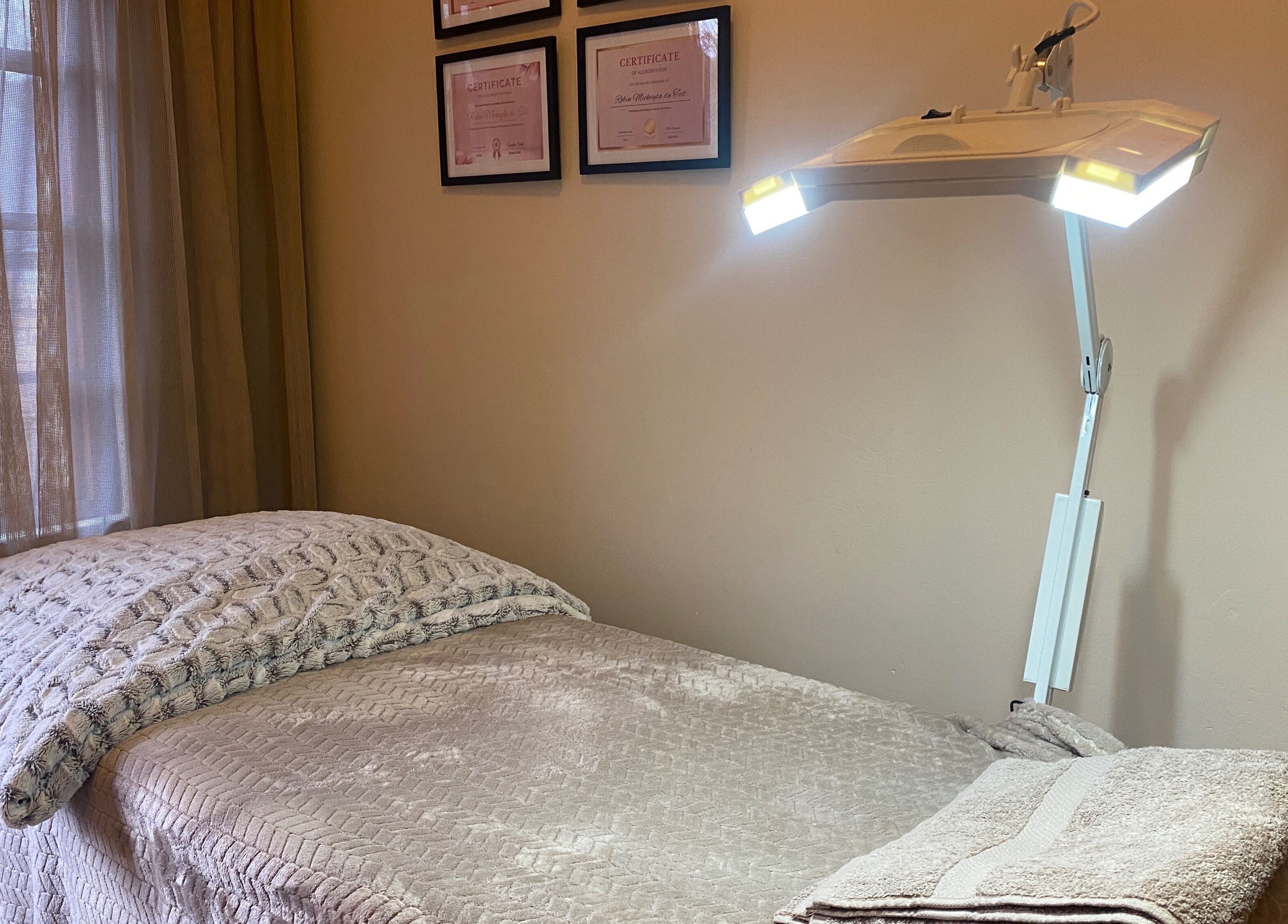 Calm treatment room at Feather Aesthetics, Bloemfontein, Free State, ZA featuring a cozy bed and soft lighting.