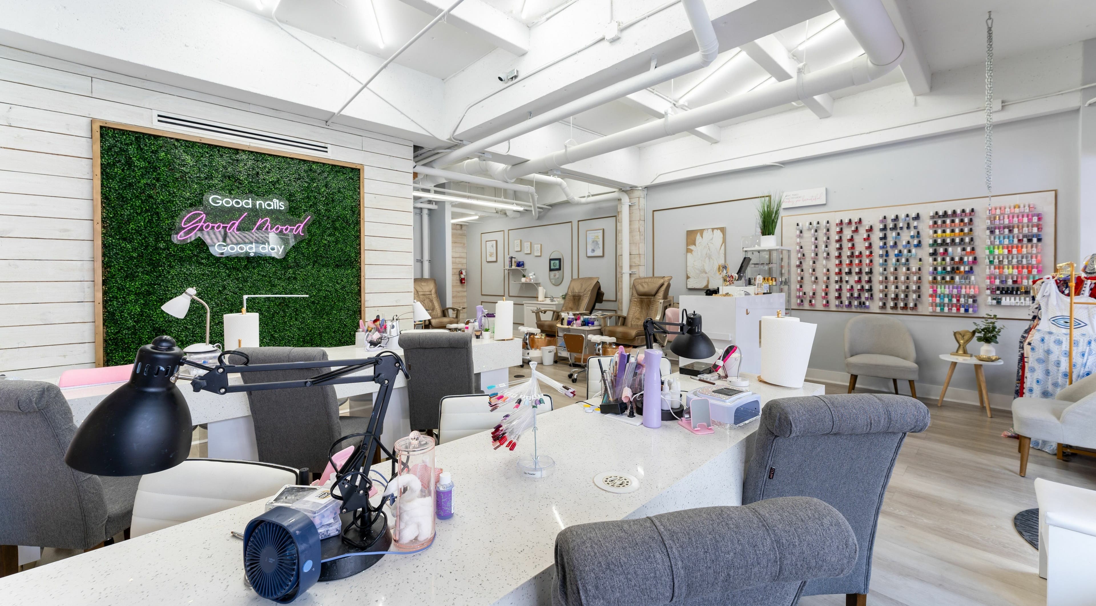 Modern interior of Nail Nova Salon & Spa in Miami Lakes, Florida, showcasing manicure stations and vibrant nail polish wall.
