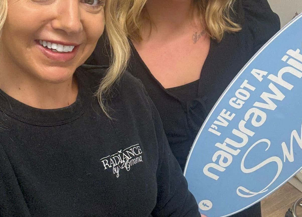 Happy clients with dazzling smiles holding a sign at B-Radiant, Glynneath, Wales, GB.