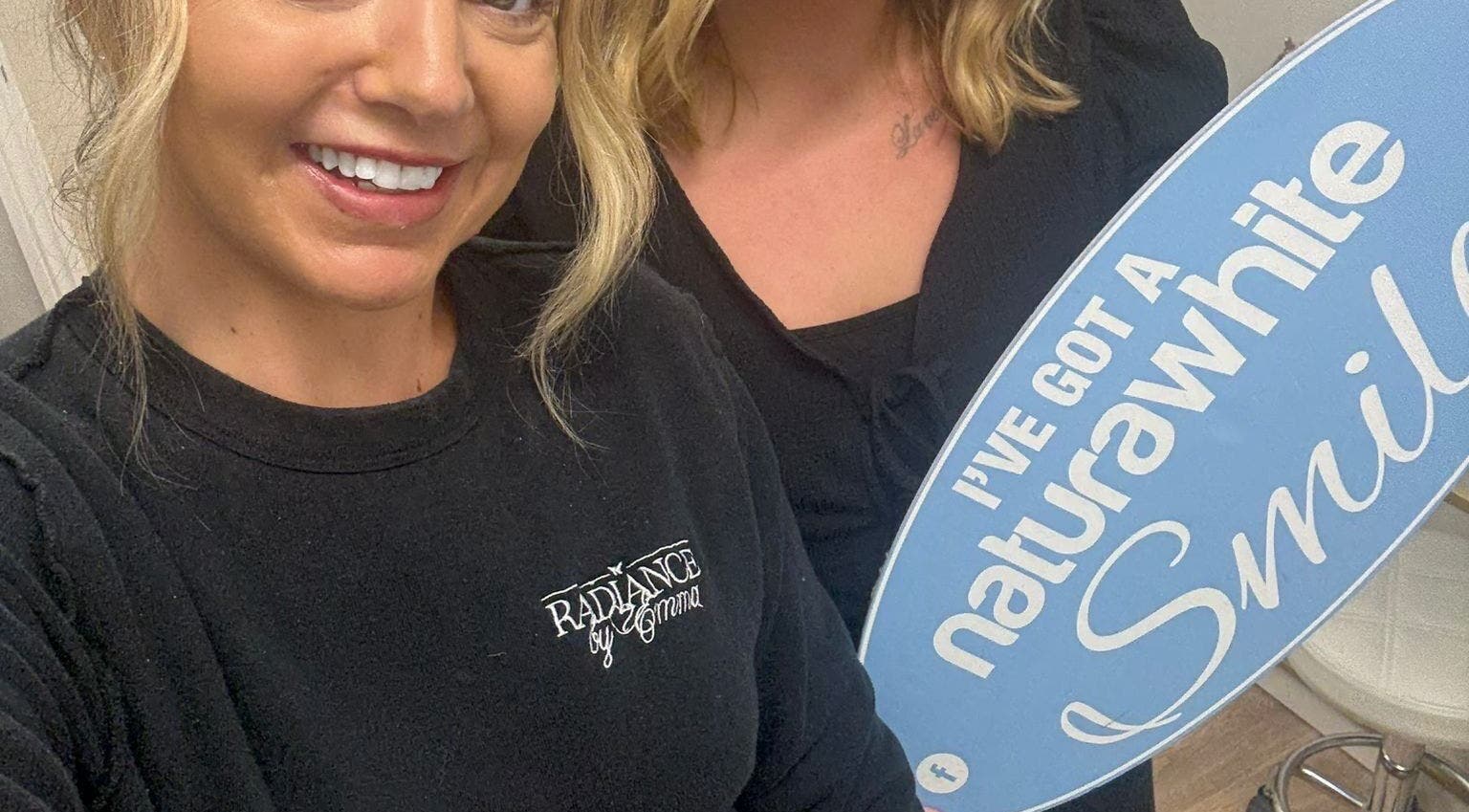 Happy clients with dazzling smiles holding a sign at B-Radiant, Glynneath, Wales, GB.