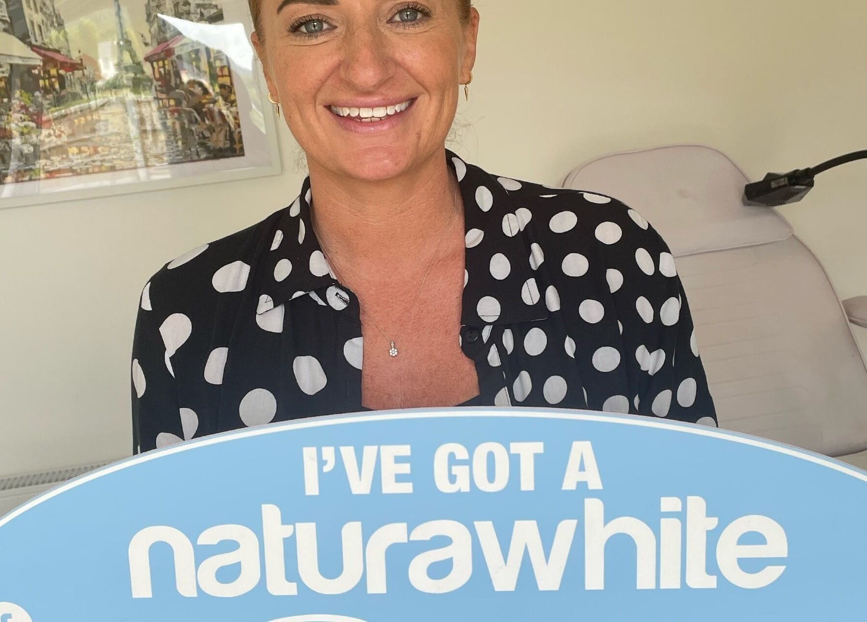 Smiling woman holding a 'naturawhite' sign at B-Radiant in Glynneath, Wales, GB.