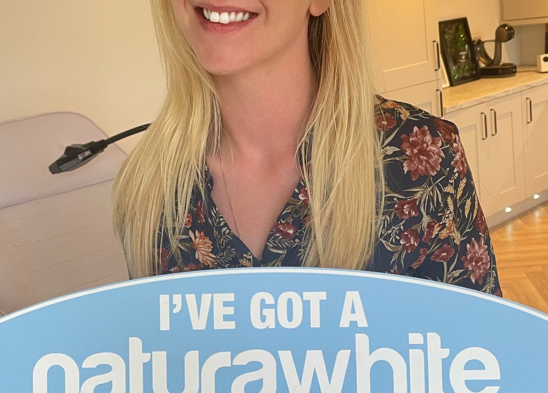 A smiling person holding a Natural White sign at B-Radiant in Glynneath, Wales, GB.