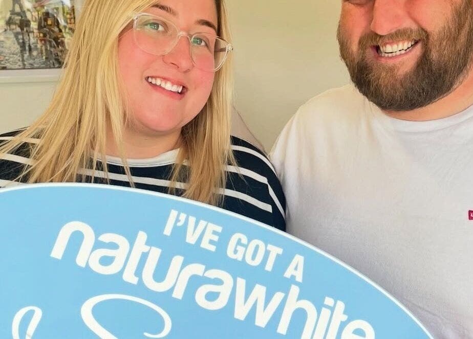 Visitors at B-Radiant Glynneath, Wales, GB holding a whitening sign, smiling warmly.