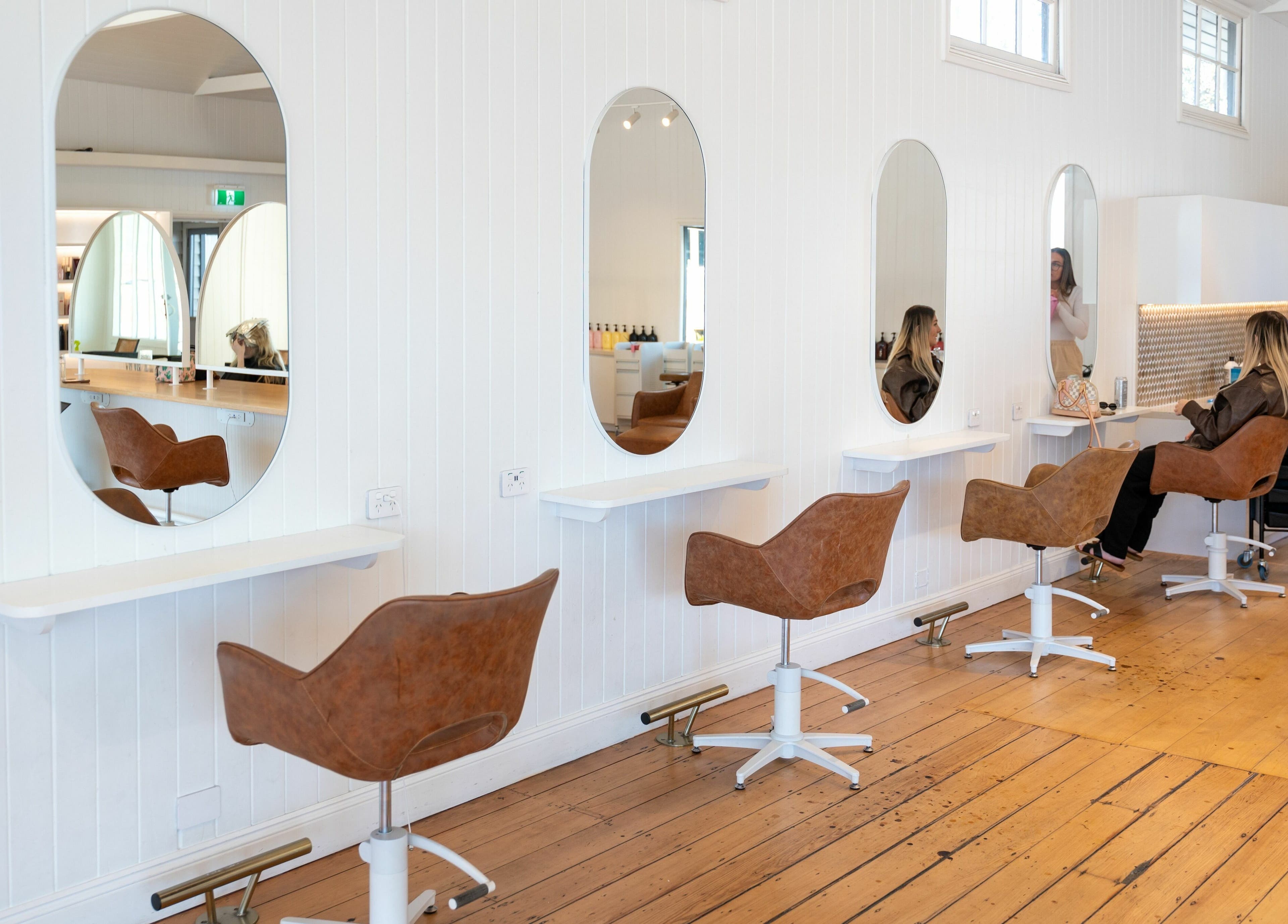 Chic salon interior at The Mane Society, Kelvin Grove, Queensland, AU, showcasing stylish brown chairs and oval mirrors.