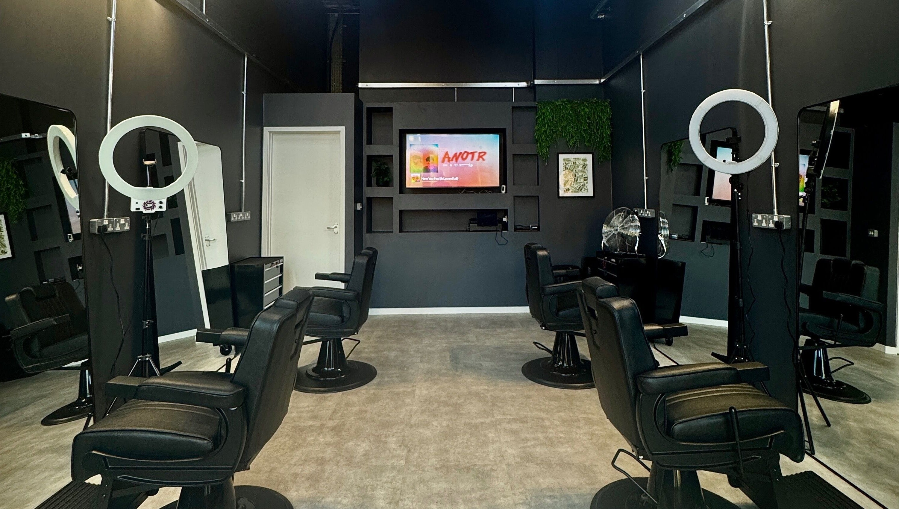 Chic interior of Sevens Barbershop in Exeter, England, GB showcasing modern black barber chairs and stylish decor.