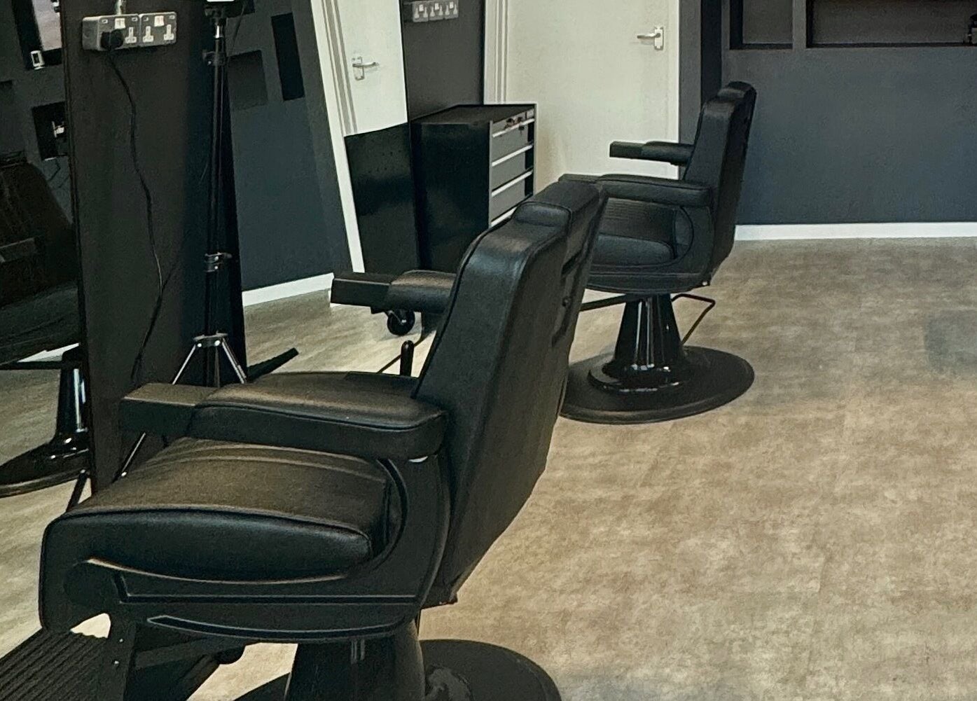 Modern interior of Sevens Barbershop in Exeter, England, GB, featuring sleek black barber chairs.