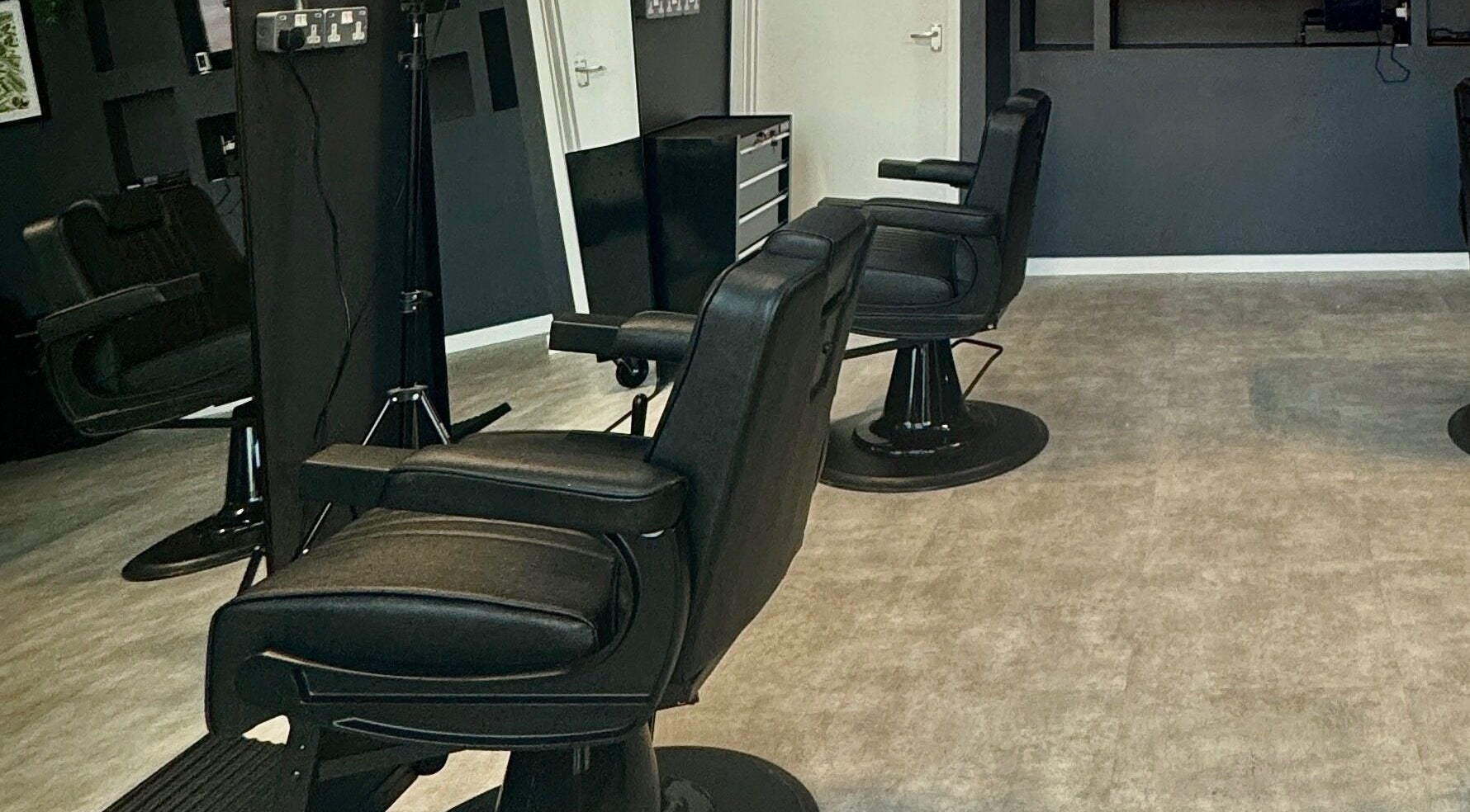 Modern interior of Sevens Barbershop in Exeter, England, GB, featuring sleek black barber chairs.