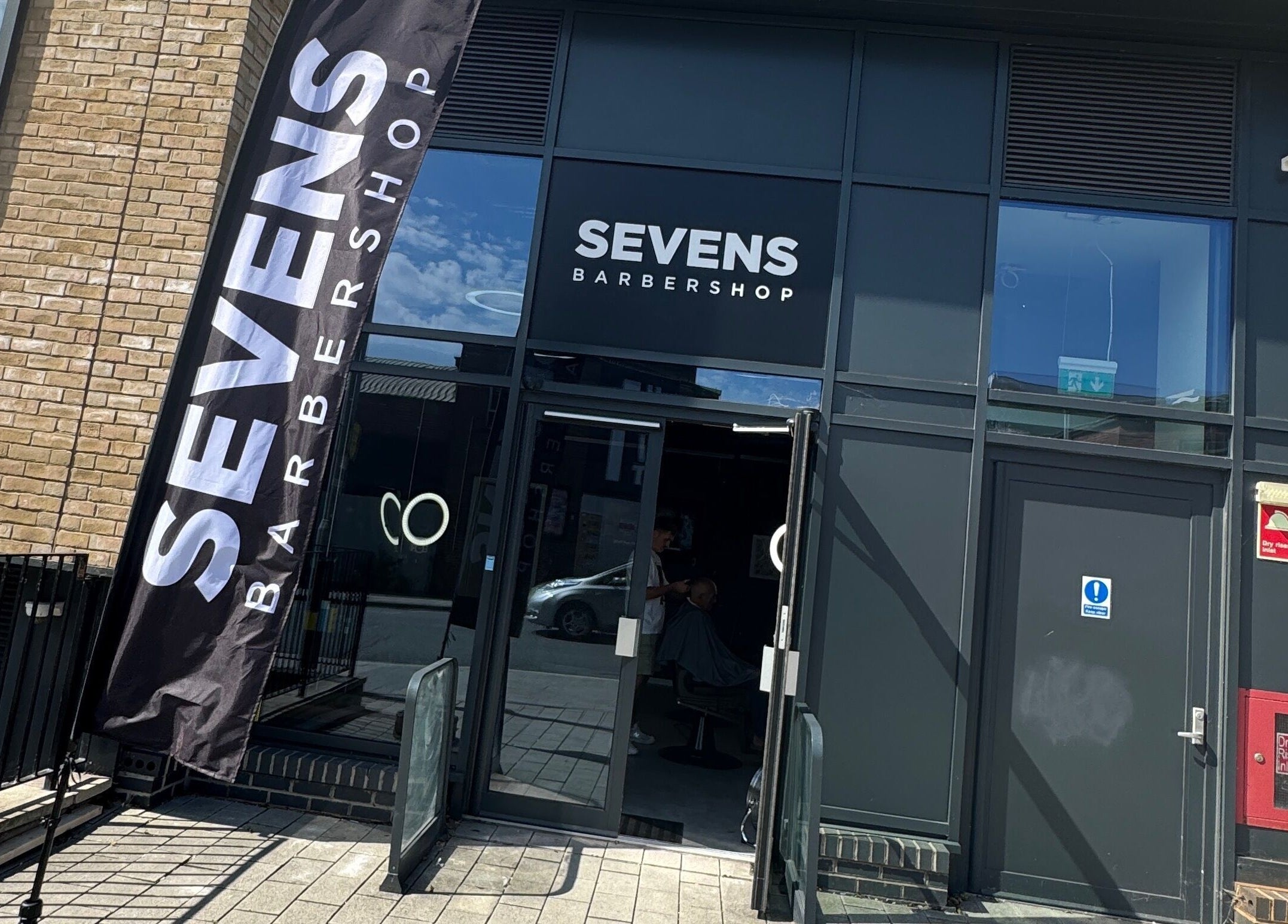 Entrance of Sevens Barbershop in Exeter, England, GB with stylish modern design and clear signage.