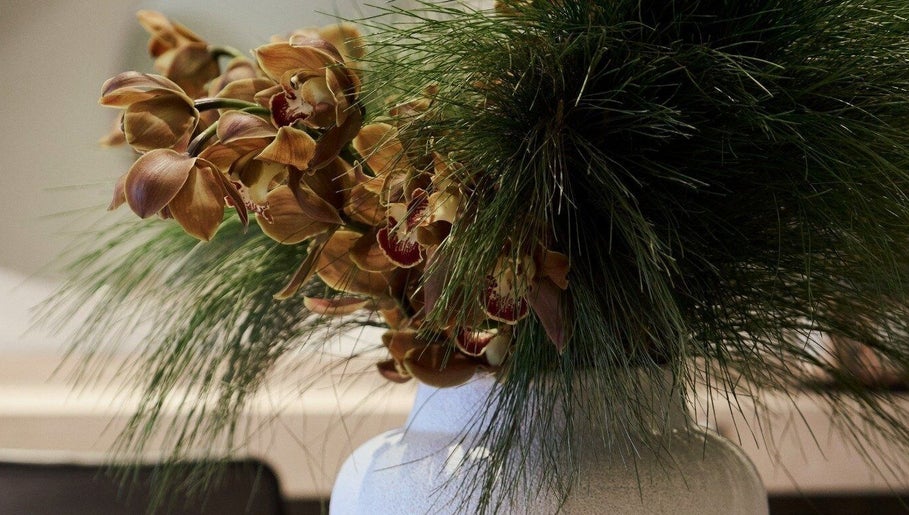 Elegant floral arrangement at Clipso Hair, Castlecrag, NSW, AU, featuring orchids and green foliage.